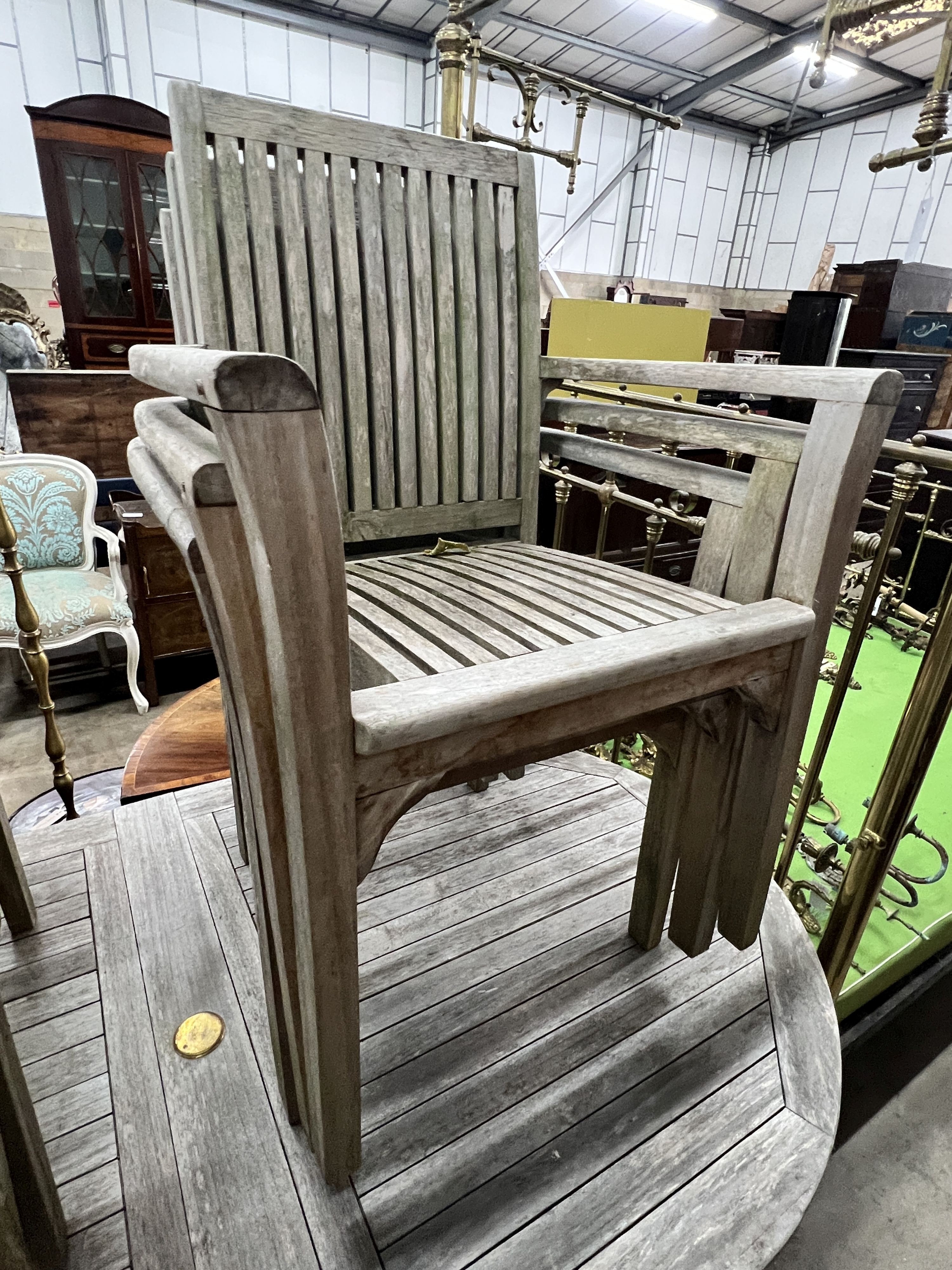 An oval weathered teak extending garden table, width 180cm, depth 100cm, height 76cm and six teak stacking chairs